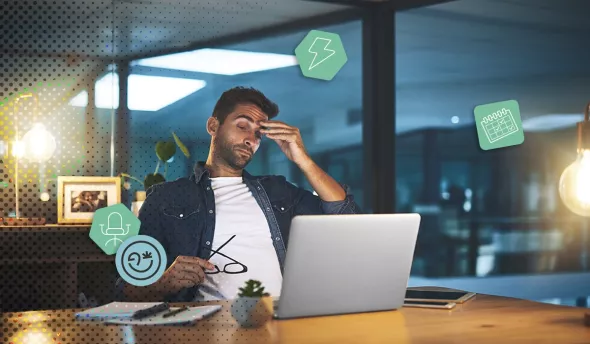 Un salarié fatigué assis devant un ordinateur, se frottant les yeux au bureau