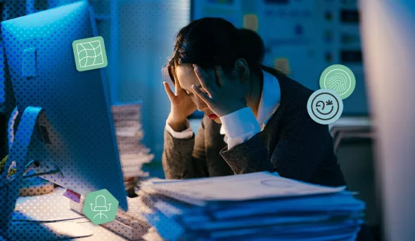 Salariée en détresse face à une pile de dossiers, assise devant un écran