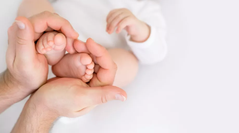 père tenant pieds de son bébé