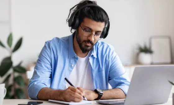 un homme avec un casque audio qui écrit