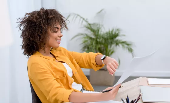 Femme au bureau qui regarde sa montre