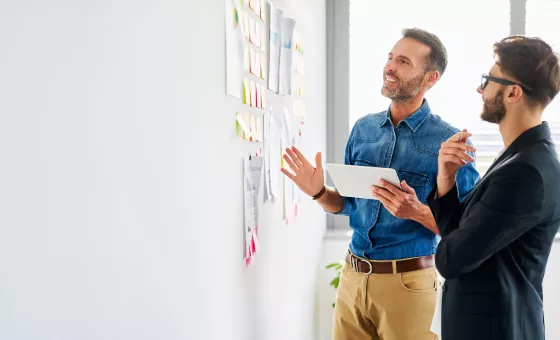 deux hommes devant un mur de post-it