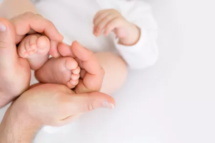 père tenant pieds de son bébé