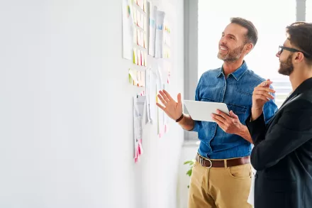 deux hommes devant un mur de post-it