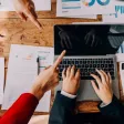 Ordinateur sur une table avec des personnes qui le pointe du doigt