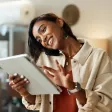 Jeune femme souriante en conversation téléphonique avec une tablette à la main