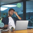 Un salarié fatigué assis devant un ordinateur, se frottant les yeux au bureau