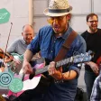 Groupe de musiciens de rue jouant de la guitare, violon et contrebasse avec énergie.