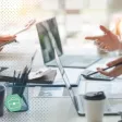 Jeune collaboratrice Zillennial échangeant avec son manager dans un espace de travail moderne, tablette à la main.