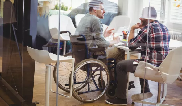 réunion entre un collaborateur en situation de handicap (fauteuil roulant) et son collègue