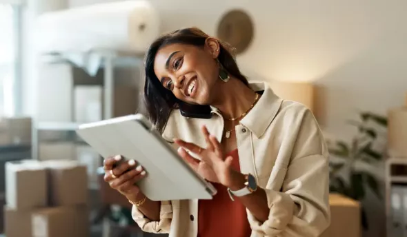 Jeune femme souriante en conversation téléphonique avec une tablette à la main