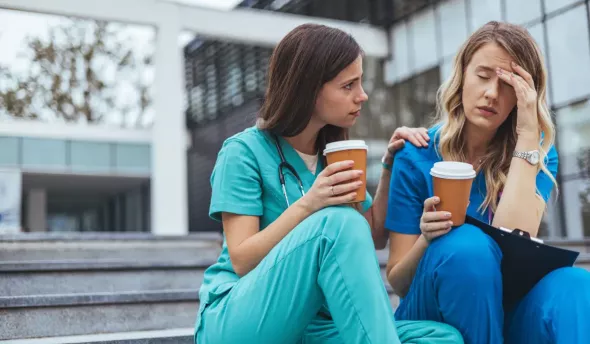 2 femmes soignantes sur un escalier, l'une d'elle semble fatiguée