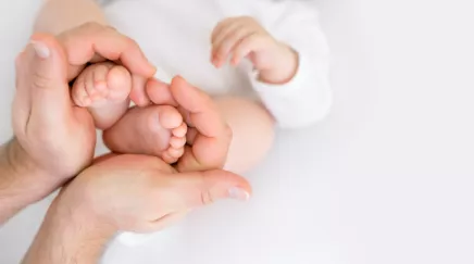 père tenant pieds de son bébé