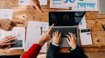 Ordinateur sur une table avec des personnes qui le pointe du doigt