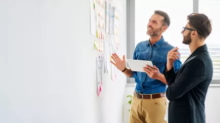 deux hommes devant un mur de post-it