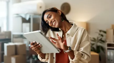 Jeune femme souriante en conversation téléphonique avec une tablette à la main