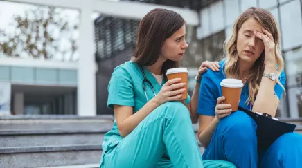 2 femmes soignantes sur un escalier, l'une d'elle semble fatiguée