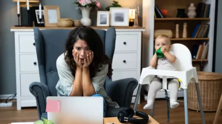 mère en train de travailler avec son bébé à côté dans une chaise haute