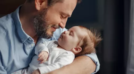 père avec son bébé endormi dans les bras