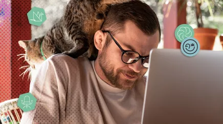 Homme travaillant sur un ordinateur portable avec un chat perché sur son épaule