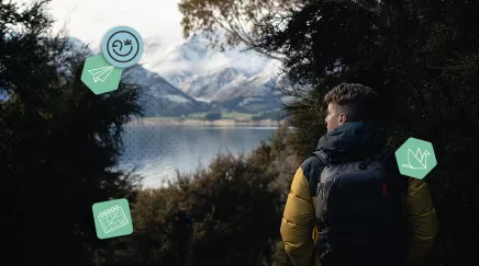 Personne en backpack (sac à dos) dans la forêt contemplant les montagnes enneigées et le lac Hawea, île du Sud de la Nouvelle-Zélande